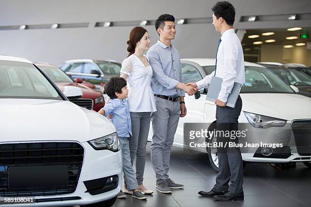 young family choosing car in showroom - young choice beijing activity stock pictures, royalty-free photos & images