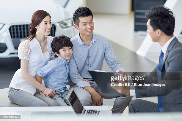 young family buying car in showroom - young choice beijing activity stock pictures, royalty-free photos & images