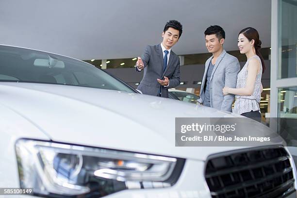 young couple choosing car in showroom - pekín express fotografías e imágenes de stock