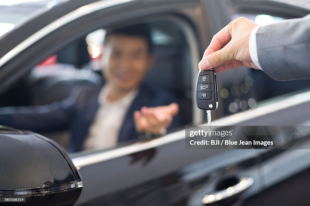 Young businessman buying car in showroom