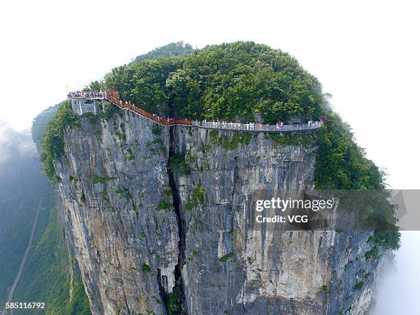 Aerial view of tourists walking on the 100-meter-long and 1.6-meter-wide glass skywalk clung the cliff of Tianmen Mountain in Zhangjiajie National...