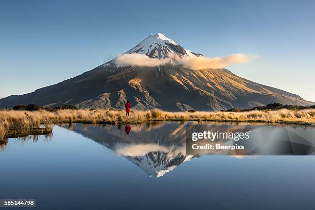 alone person was looking at mount taranaki. the shadow reflected in the lake at mount egmont in new zealand. - new zealand volcano stock pictures, royalty-free photos & images