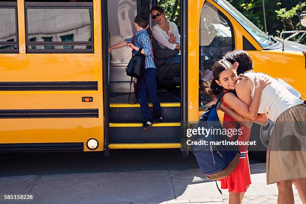 mother greeting elementary age girl getting off school bus. - school bus kids stock pictures, royalty-free photos & images