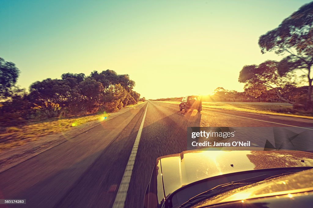 Cars driving towards the sun on highway