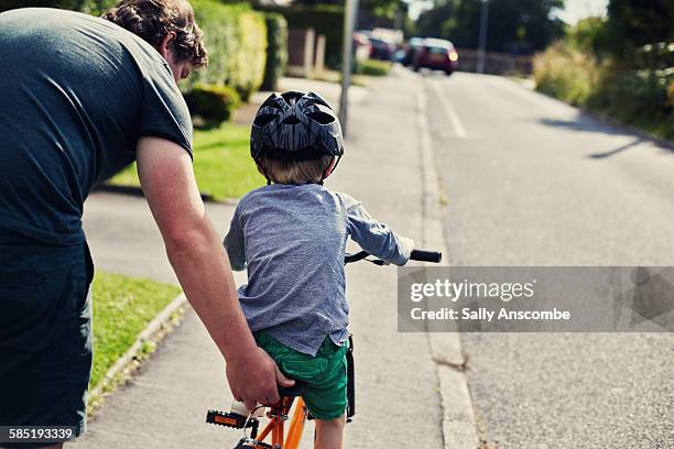 little boy learning to ride a bicycle - child and parent and bike stock-fotos und bilder