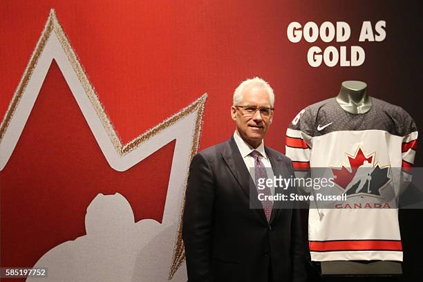 Head of Hockey Canada Thomas "Tom" Renney shows off the new Team Canada Jersey. Rows of Maple Leaf icons fill the jersey's shoulder caps. The jersey...