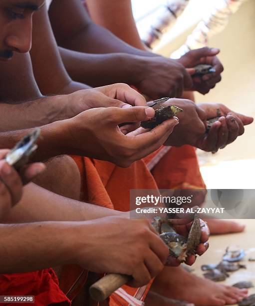 Kuwaitis look for pearls in shells that divers picked from the sea during the annual pearl diving season on August 2, 2016 off the coast of the port...