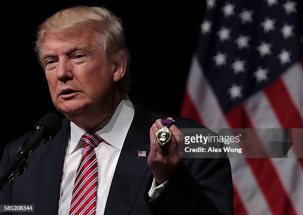 Republican presidential nominee Donald Trump holds a Purple Heart, given to him by veteran Louis Dorfman, during a campaign event at Briar Woods High...