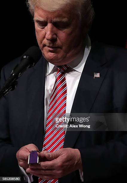 Republican presidential nominee Donald Trump looks at the Purple Heart given to him by veteran Louis Dorfman during a campaign event at Briar Woods...