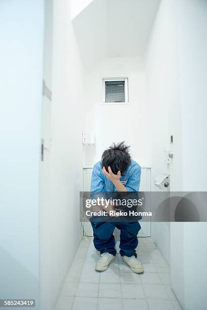 man sitting on toilet using smart phone - japanese human toilet stock pictures, royalty-free photos & images