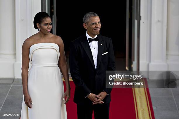 President Barack Obama, right, and U.S. First Lady Michelle Obama wait during an arrival for Singapore Prime Minister Lee Hsien Loong, not pictured,...