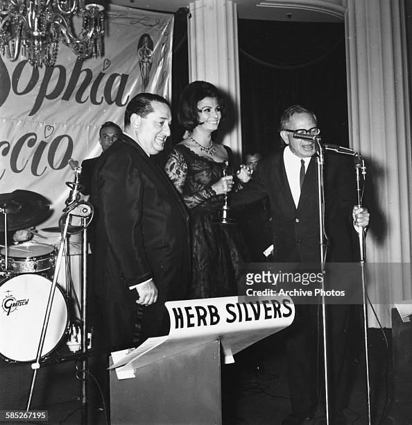 Actress Sophia Loren on stage with Joseph Levine and Vice President of the Academy Geoffrey Scurlock, receiving her Best Actress Oscar for the film...