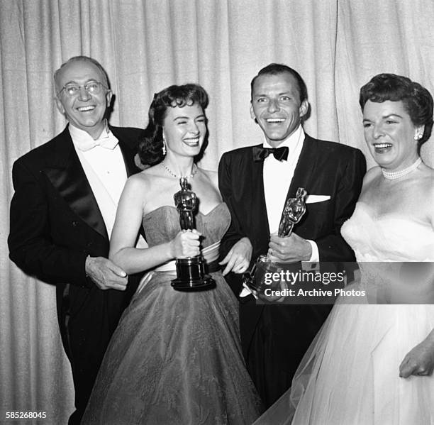 Actors Frank Sinatra and Donna Reed holding their supporting actor Oscars, both for the film 'From Here to Eternity', with presenters Walter Brennan...