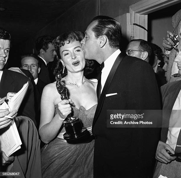 Actress Donna Reed holding her Oscar for the film 'From Here to Eternity', being kissed on the cheek by fellow winner William Holden, at the 26th...