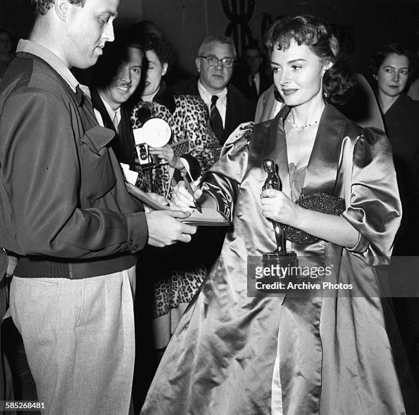 Actress Donna Reed holding her Oscar for the film 'From Here to Eternity', signing an autograph for a fan as she leaves the 26th Academy Awards,...