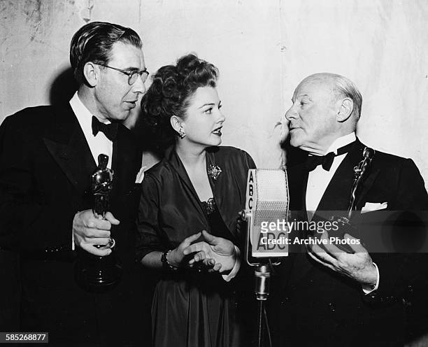 Actor Edmund Gwenn and writer George Seaton holding their Oscars for the film 'Miracle on 34th Street', with presenter Anne Baxter, at the 20th...