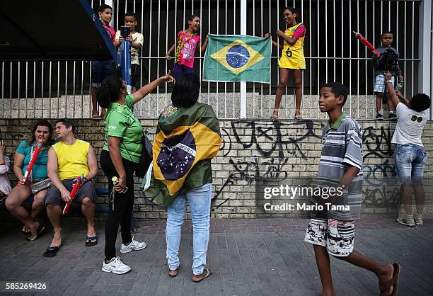 Brazilians pose with a Brazil flag ahead of the arrival of the Olympic torch ahead of the Rio 2016 Olympic Games on August 2, 2016 in Sao Goncalo,...
