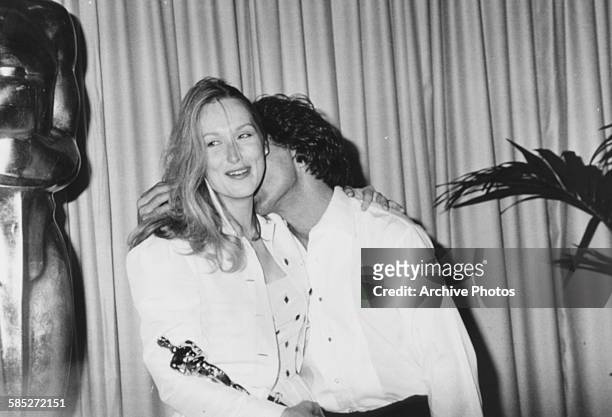 Actress Meryl Streep holding her Oscar award, for the film 'Kramer vs Kramer' and being kissed on the neck by co-star Dustin Hoffman, at the 52nd...