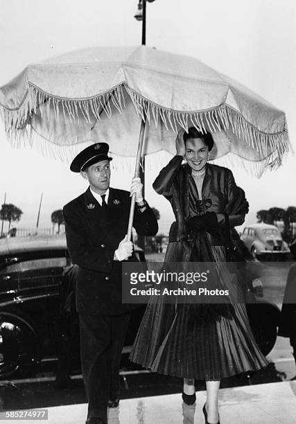 Actress Rita Hayworth having an umbrella held over her as she leaves her car at the Cannes Film Festival, April 24th 1952.
