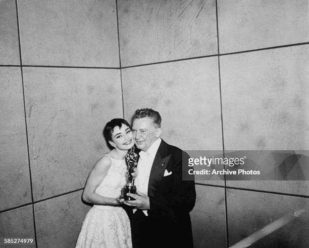 Actress Audrey Hepburn holding her Best Actress Oscar for the film 'Roman Holiday', with actor Jean Hersholt, at the 26th Academy Awards, New York,...