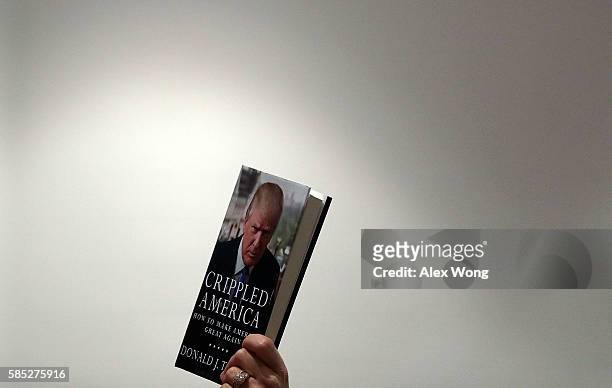 Supporter of Republican presidential nominee Donald Trump holds up a copy of his book "Crippled America: How to Make America Great Again" during a...