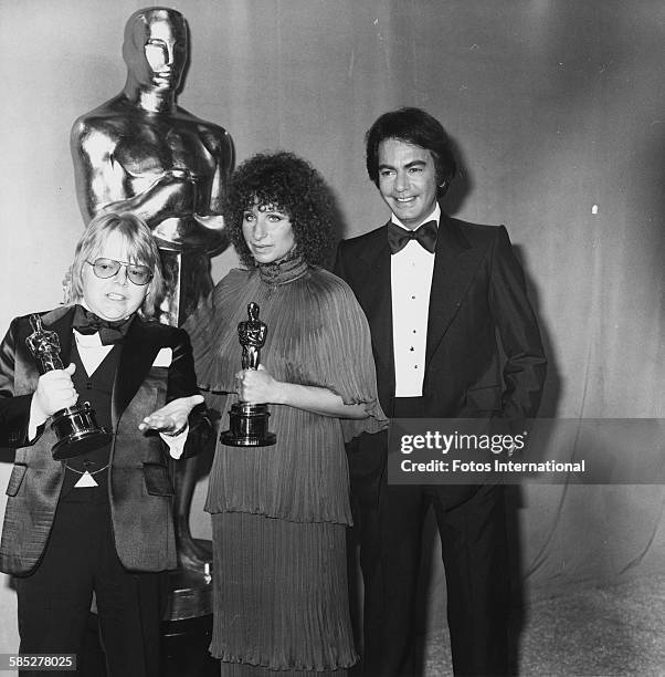 Musicians Paul Williams and Barbra Streisand holding their Oscars for Best Original Song, with presenter Neil Diamond, at the 49th Academy Awards,...