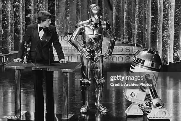 Actor Mark Hamill presenting an award with his Star Wars co-stars C3PO and R2D2, at the 50th Academy Awards, Los Angeles, April 3rd 1978.