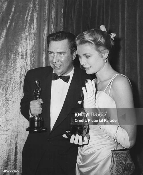 Actor Edmond O'Brien holding his Best Supporting Actor Oscar for the film 'The Barefoot Contessa', and Grace Kelly with her Oscar for 'The Country...