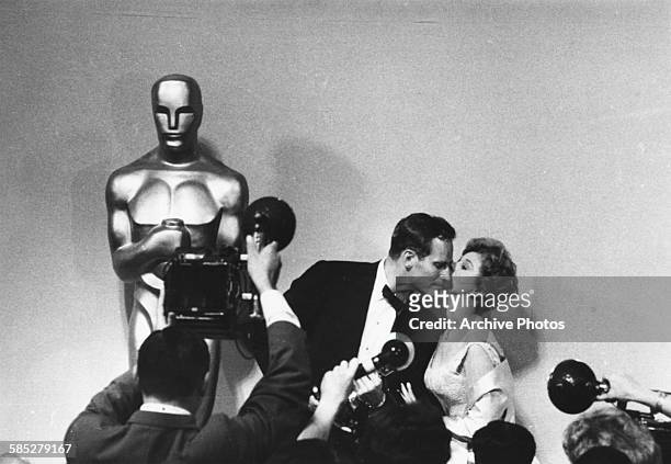 Actress Susan Hayward kissing Charlton Heston on the cheek in front of a bank of photographers after he received his Oscar for the film 'Ben Hur', at...