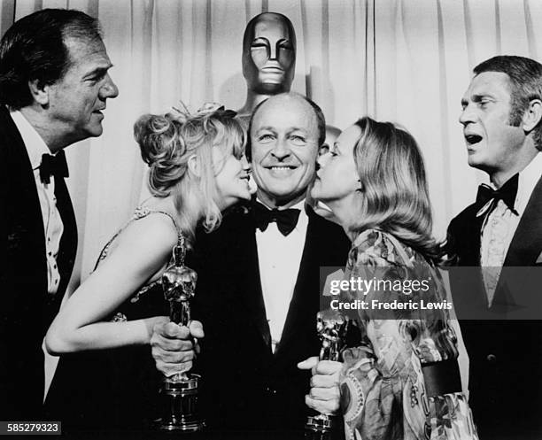 American actress Goldie Hawn and French actress Jeanne Moreau kiss American film producer, and former military officer, Frank McCarthy on each cheek,...