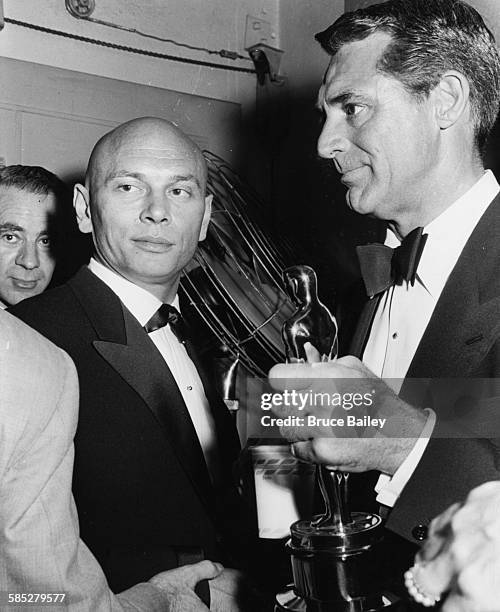 Actor Cary Grant holding an Oscar statuette with Best Actor winner Yul Brynner, who won for 'The King and I', at the 29th Academy Awards, Hollywood,...