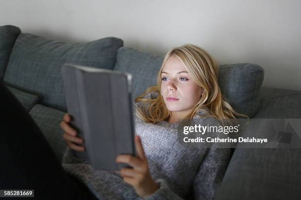 a 18 years old young woman with a tablet computer - lying on back girl on the sofa stock pictures, royalty-free photos & images