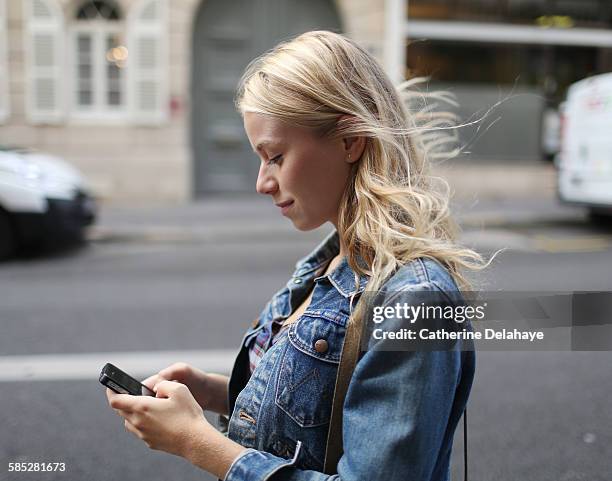 a young woman with a smartphone in the street - girl side view stockfoto's en -beelden
