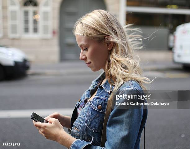 a young woman with a smartphone in the street - blonde hair girl stock pictures, royalty-free photos & images