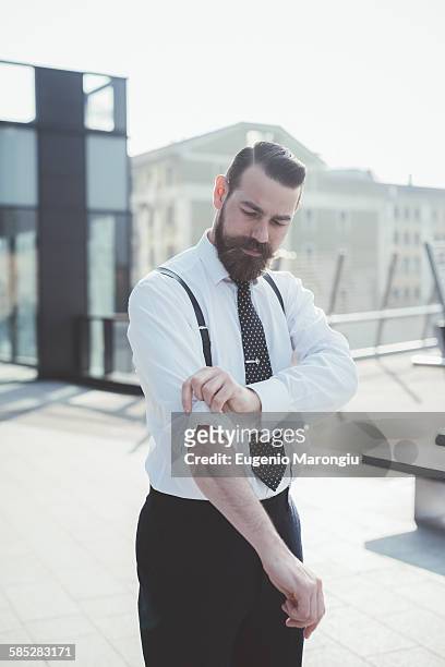 stylish businessman rolling up sleeves on footbridge - sleeve roll stock pictures, royalty-free photos & images