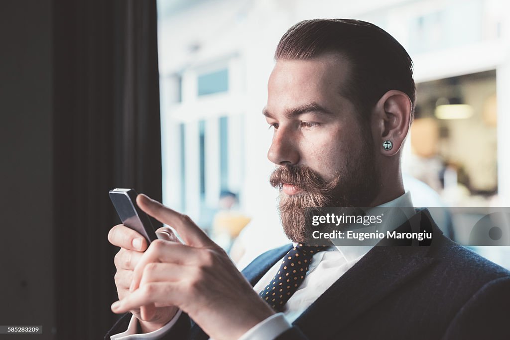 Businessman reading smartphone update in cafe