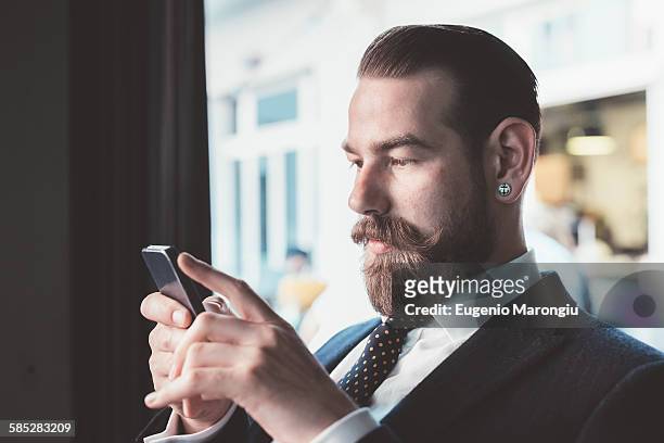 businessman reading smartphone update in cafe - bigote manillar fotografías e imágenes de stock