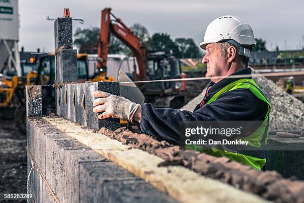 workers laying bricks on construction site - concrete block stock pictures, royalty-free photos & images