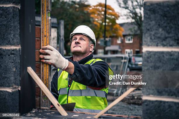 workers laying bricks on construction site - bricklayer stock pictures, royalty-free photos & images