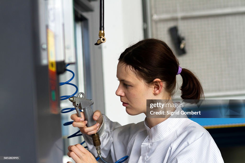 Side view of young woman using compressor gun