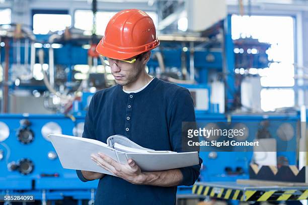 factory engineer reading machinery instruction manual - manuale foto e immagini stock