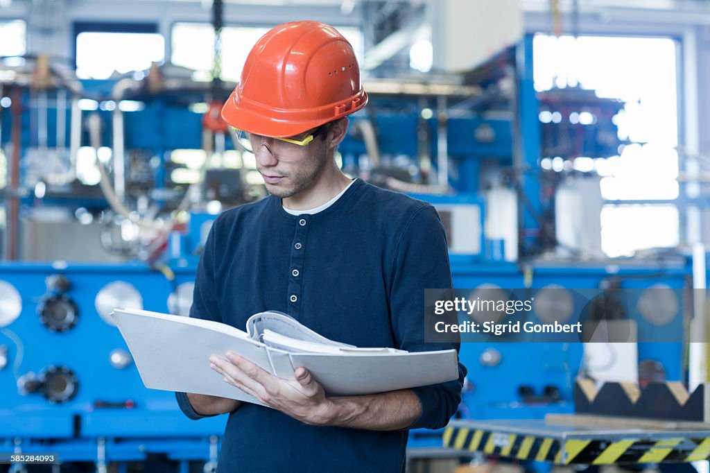 Factory engineer reading machinery instruction manual