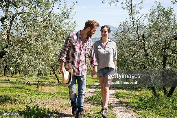 full length front view of couple walking on dirt track hand in hand - wellness olive tree stock pictures, royalty-free photos & images