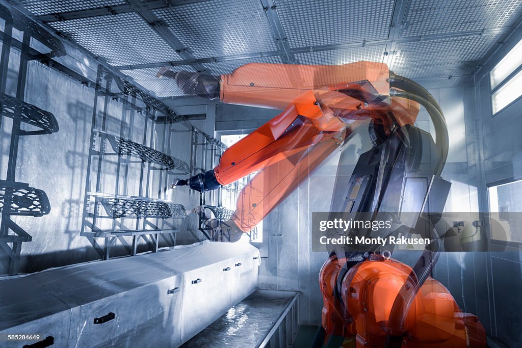 Multiple exposure of robot spray painting automotive parts in spray paint factory, close up