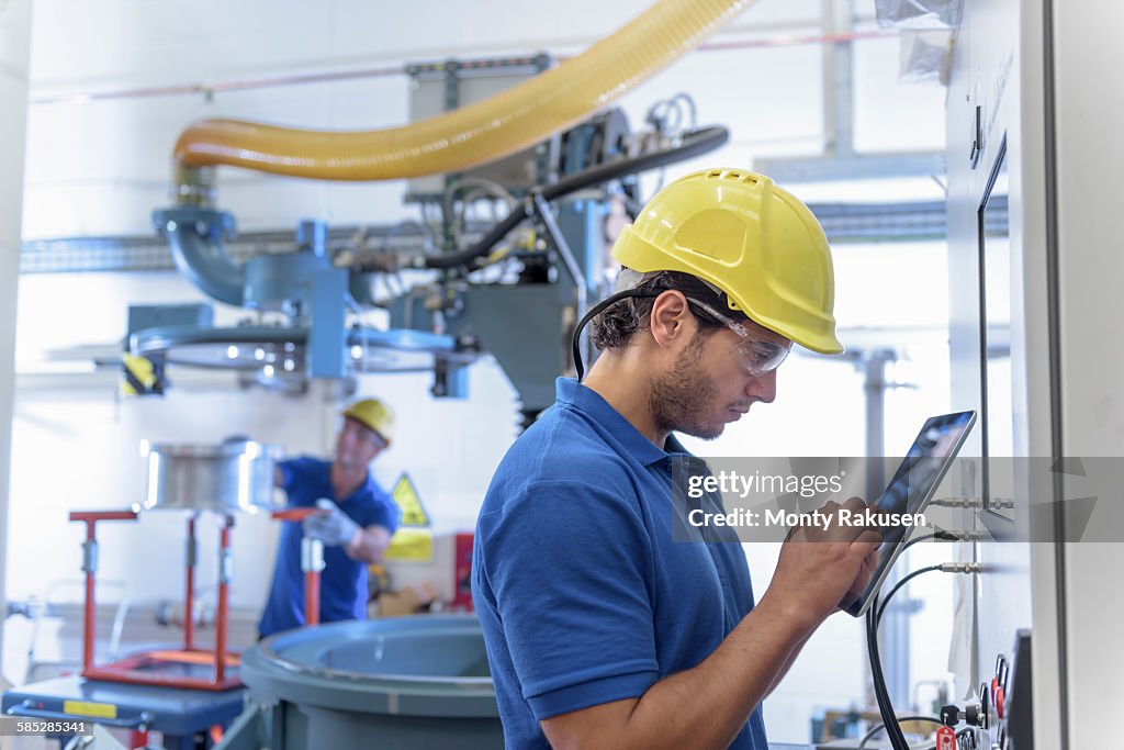 Workers operating environmental testing equipment with digital tablet in electronics factory