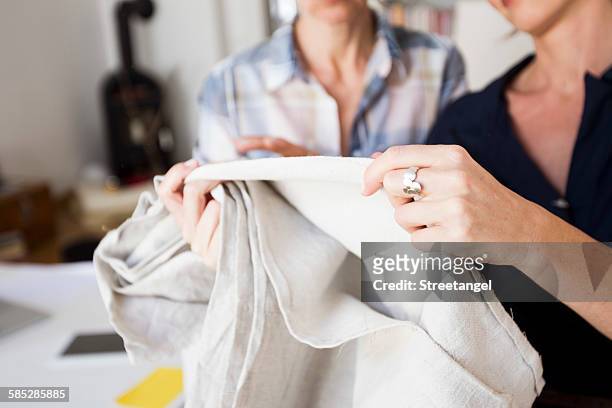 cropped view of mature women holding and inspecting fabric - touching fabric stock pictures, royalty-free photos & images