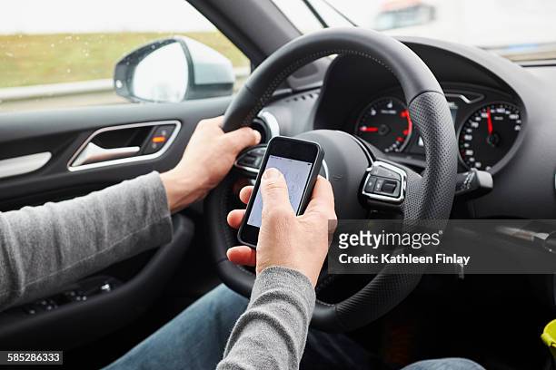 cropped shot of man using smartphone whilst driving - distracted driving stock pictures, royalty-free photos & images