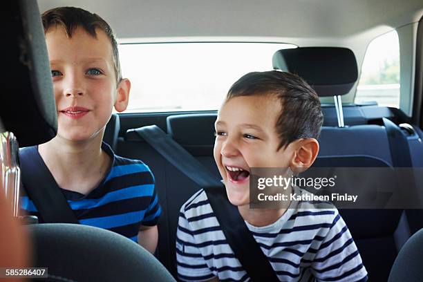 two happy young brothers traveling in car back seat - back seat stock pictures, royalty-free photos & images