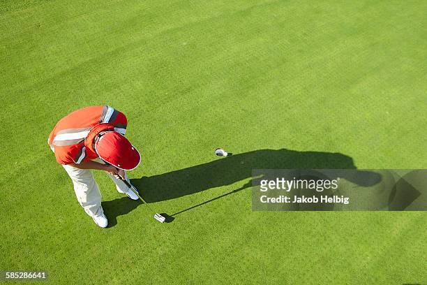 high view of golfer and shadow putting - golf putting stock pictures, royalty-free photos & images