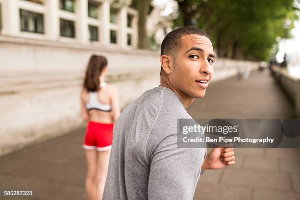 young male runner looking over his shoulder on riverside - man looking back stock pictures, royalty-free photos & images